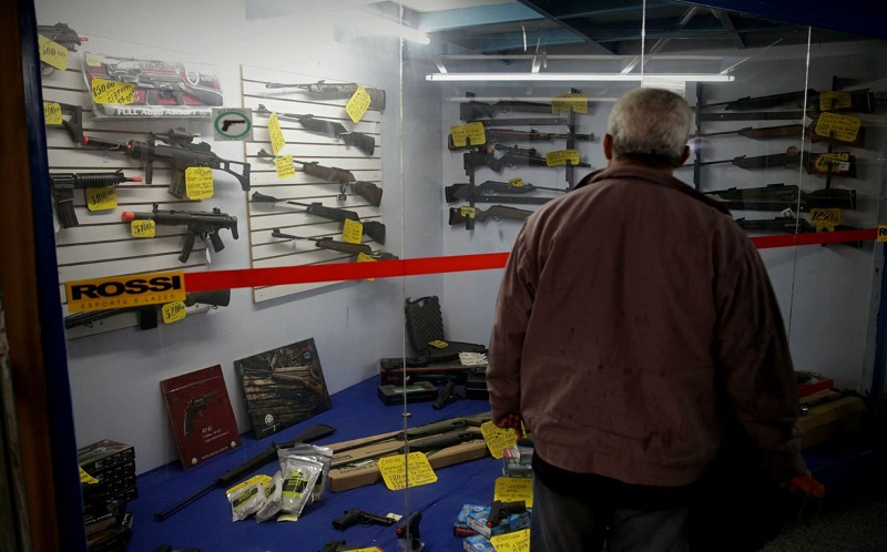 Homem observa vitrine com armas em São Paulo. Foto Fernando Bezerra EFE Homem observa vitrine com armas em São Paulo. Foto Fernando Bezerra EFE